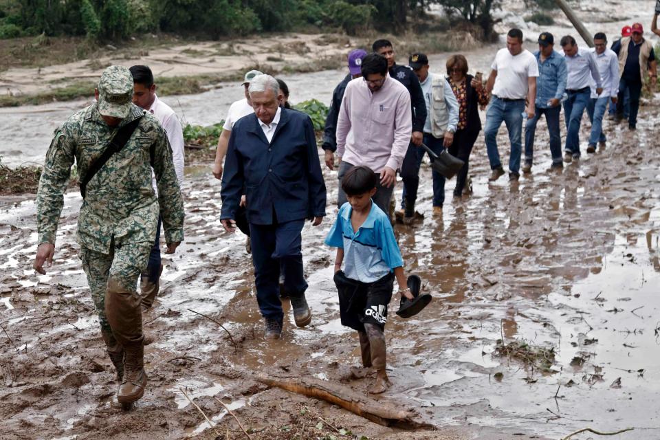 Mexico’s president Andres Manuel Lopez Obrador and members of his cabinet walk through mud as they visit a hurricane-damaged community near Acapulco on Wednesday (AFP via Getty Images)