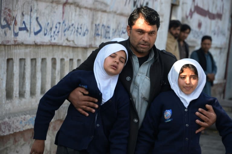 An Afghan man assists two schoolgirls in the vicinity of an attack close to the Pakistan consulate in Jalalabad, on January 13, 2016