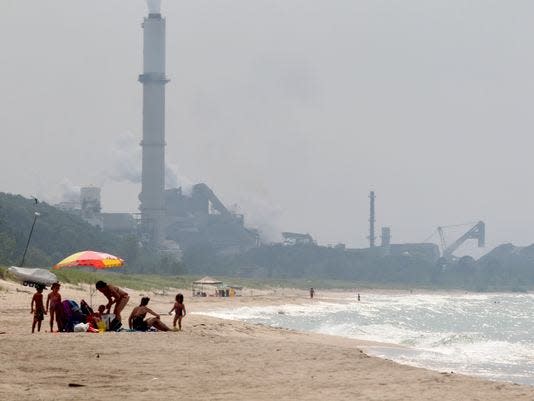 People enjoy the beach on the Indiana shore of Lake Michigan, east of Cleveland Cliffs Burns Harbor steel mill. Steelmakers and power plants make up more than three-quarters of all greenhouse gas emissions from facilities in Indiana.