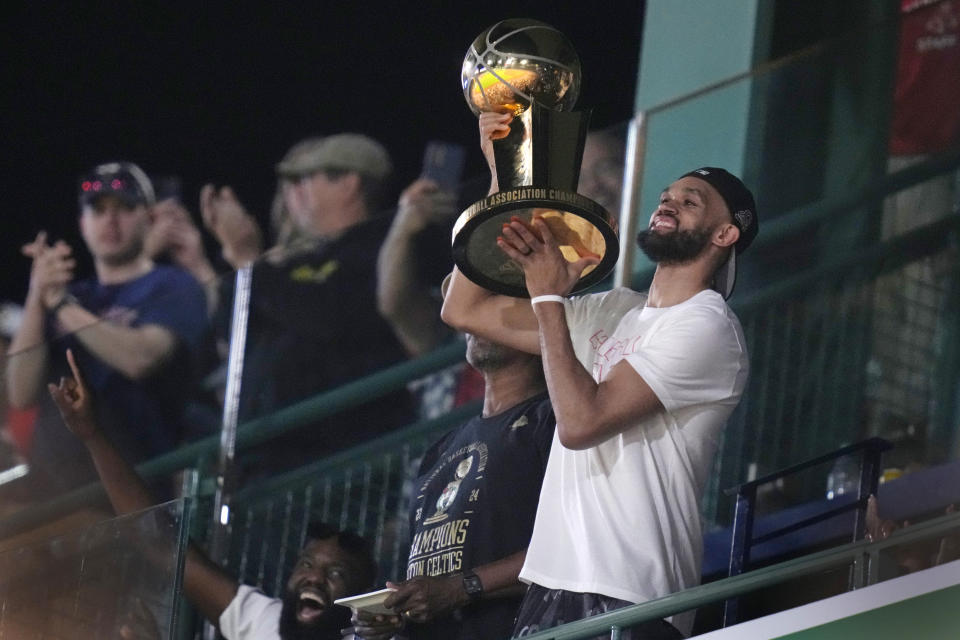 Boston Celtics' Derrick White lifts the Larry O'Brien Championship Trophy during the eighth inning of a baseball game between the Boston Red Sox and the Toronto Blue Jays at Fenway Park, Monday, June 24, 2024, in Boston. (AP Photo/Charles Krupa)