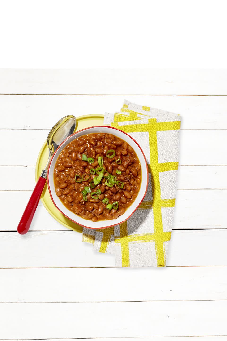 slow cooker baked beans in a bowl and sprinkled with sliced green onion on top