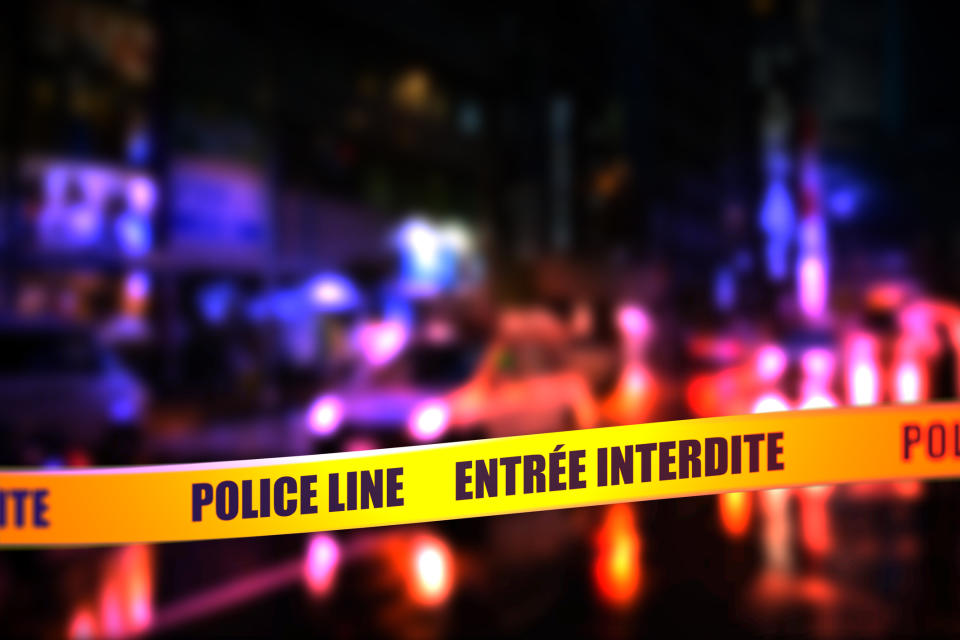 Blurred nighttime scene with a focused "POLICE LINE ENTRÉE INTERDITE" tape across the foreground