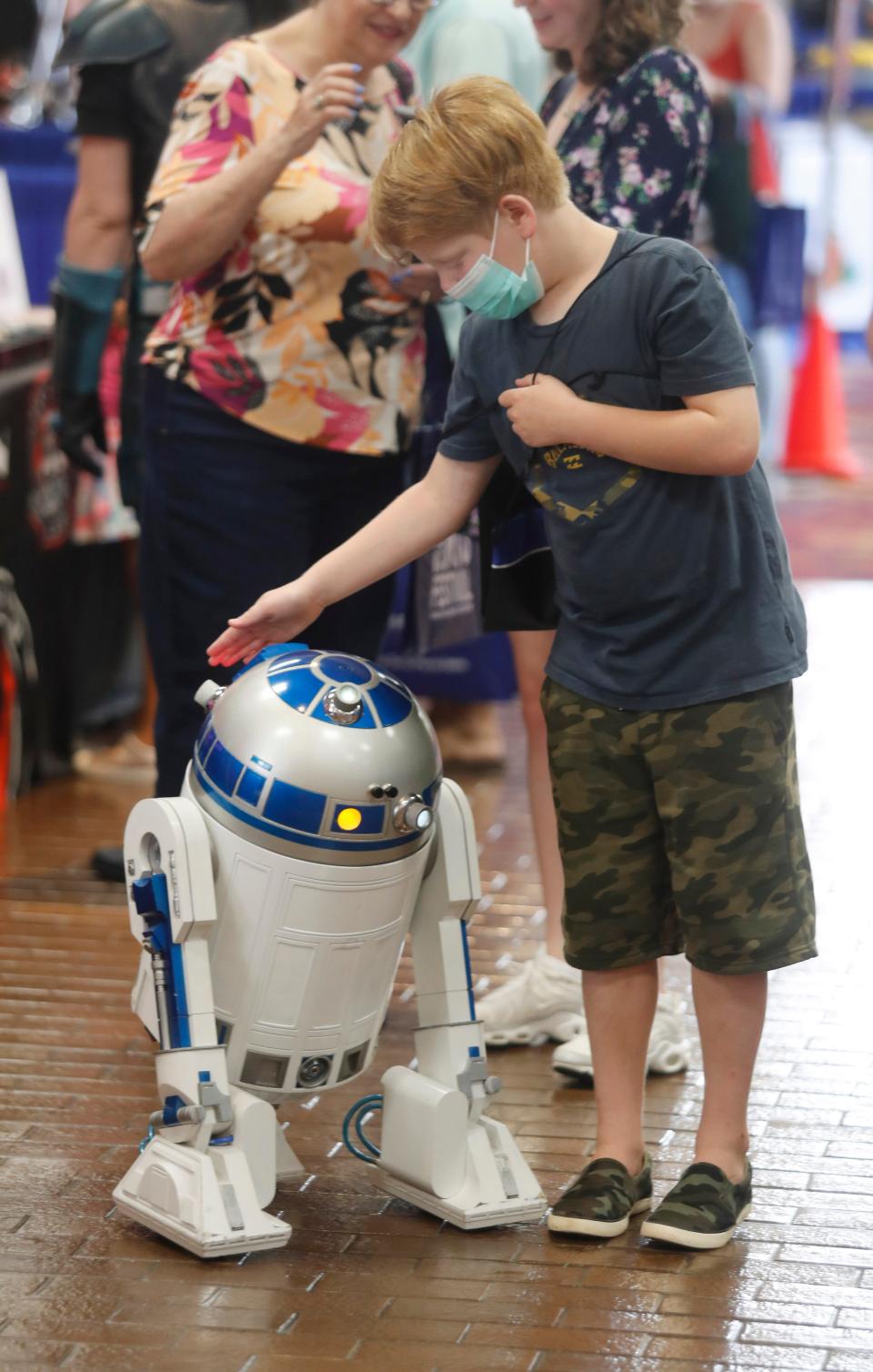 Eight-year-old Hudson James gets to know a remote controlled R2D2 robot Saturday at the Lubbock Arts Festival. The robot was made by the West Texas Droid Builders, one of seven Star Wars clubs in a booth. The theme for the show was Out of This World: A Celebration of Outer Space, Astronauts, and Space Travel.