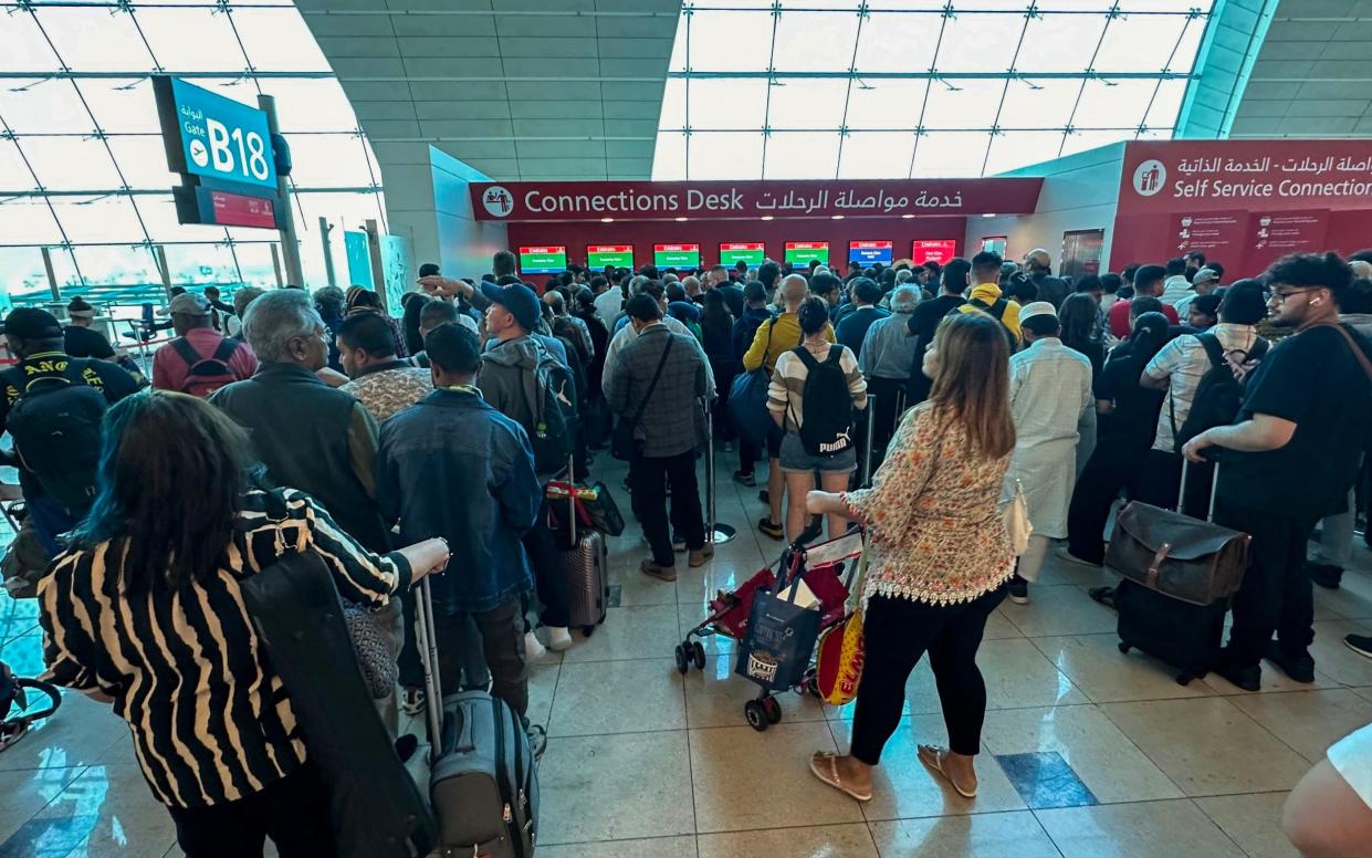 Passengers queue at a flight connection desk at the Dubai International Airport