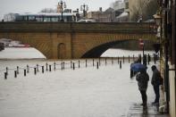 Pedestrians walk near the Ouse Bridge as the level of the River Ouse rises in York yesterday. (Getty)