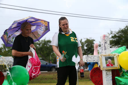 Santa Fe High School student Sierra Dean (R), with the support of Georgia Truitt, mourns the death of her friends killed in a recent shooting at a makeshift memorial left in their memory at Santa Fe High School in Santa Fe, Texas, U.S., May 23, 2018. REUTERS/Loren Elliott