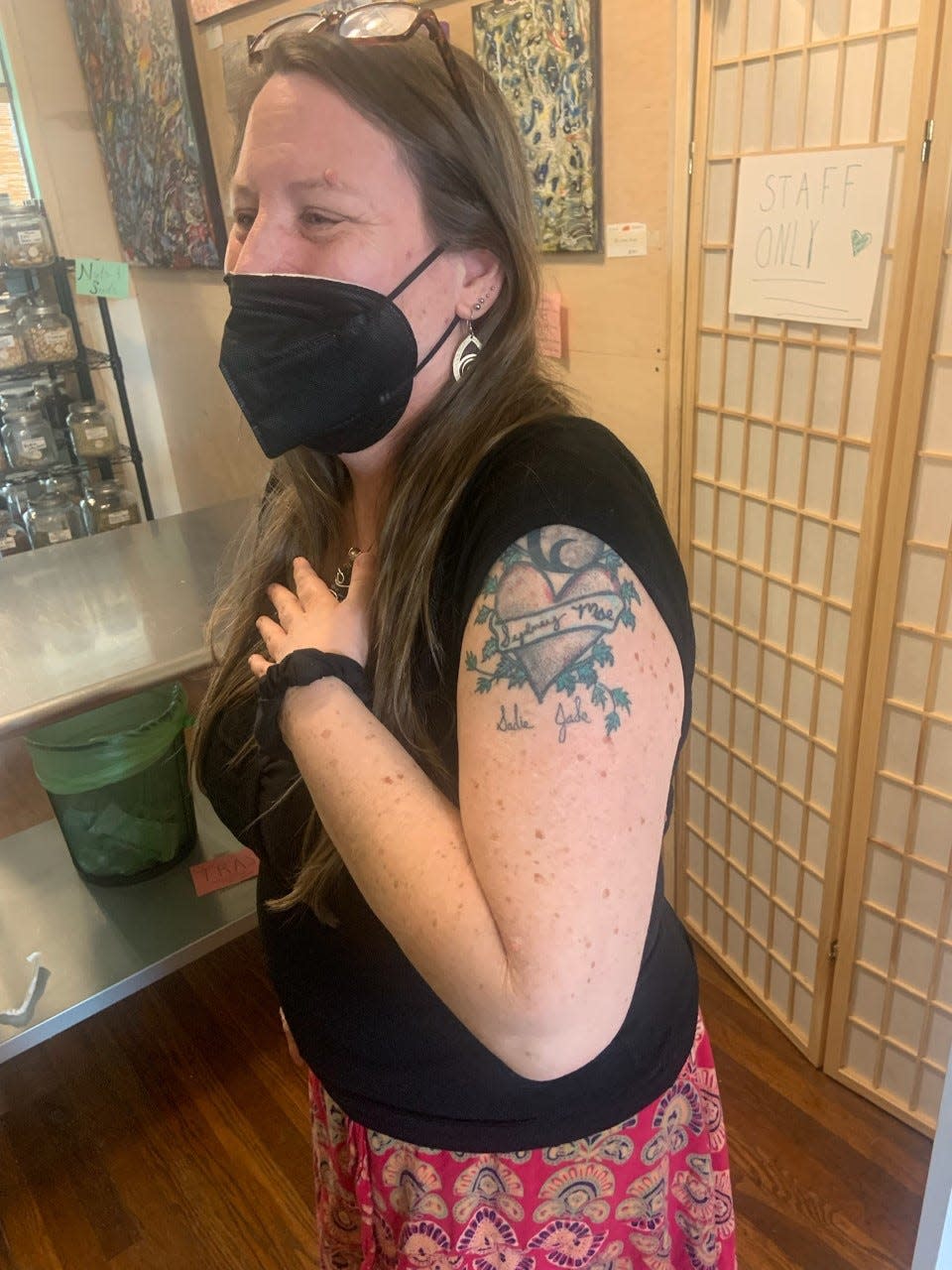 Wild Violet owner Michele Clark, 53, poses here showing her tattoo honoring her daughters, Sydney, 24, who co-owns the business, and Sadie, 10.