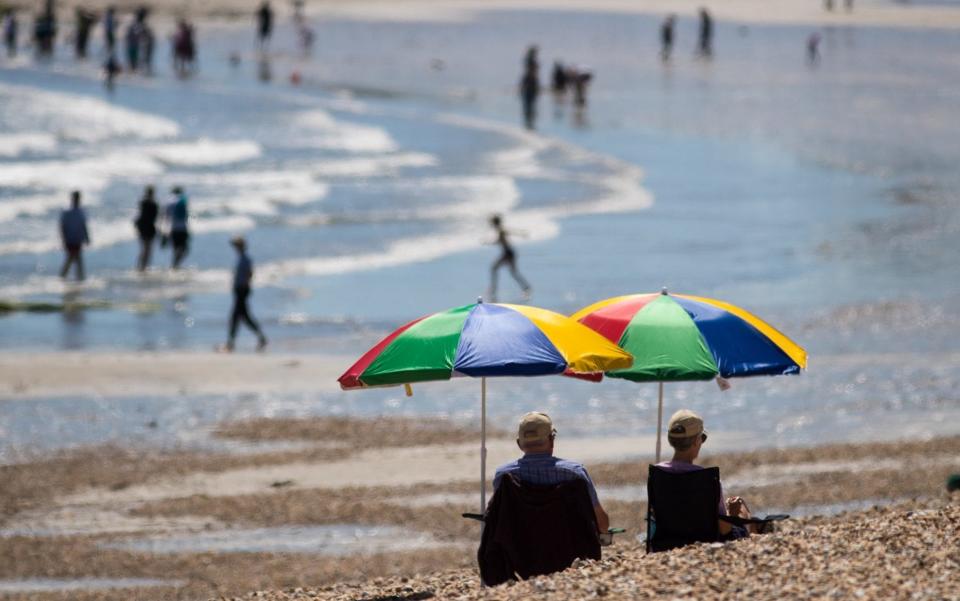 People sit beside the sea as they enjoy the fine weather on the beach in Lyme Regis in Dorset - Credit: Getty Images