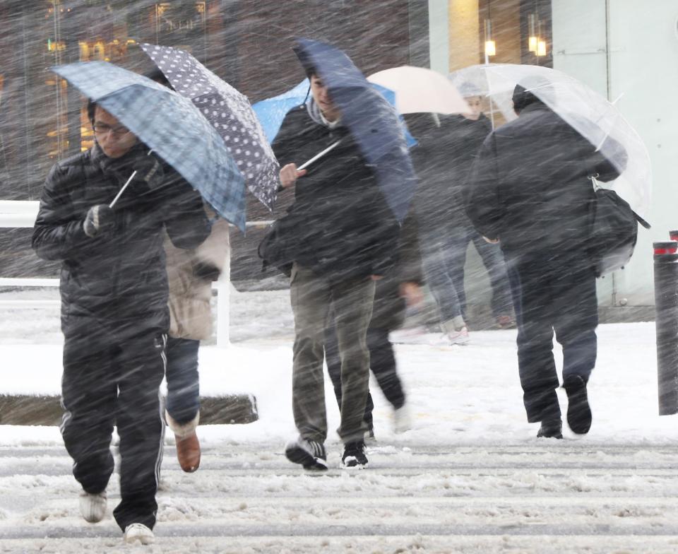 People walk against blowing snow in Tokyo, Saturday, Feb. 8, 2014. The Japan Meteorological Agency issued Saturday the first heavy snowfall warning for central Tokyo in 13 years. (AP Photo/Koji Sasahara)