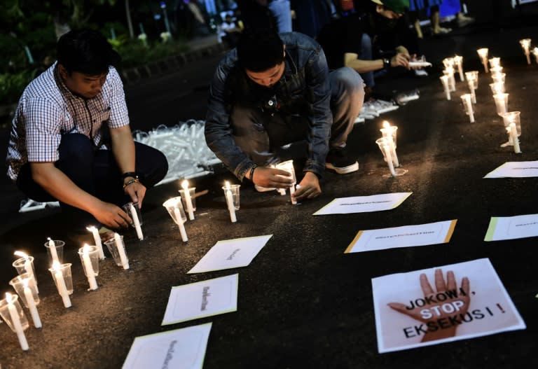 Indonesian men light candles during an anti-execution rally in front of the presidential palace in Jakarta on July 28, 2016