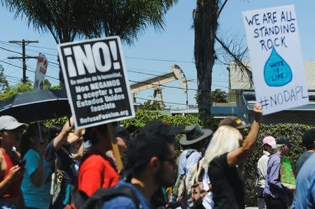 Demonstrators walk past an oil pump jack located in a residential area during People's Climate March protest for the environment in the Wilmington neighborhood in Los Angeles, California, U.S. April 29, 2017. REUTERS/Andrew Cullen