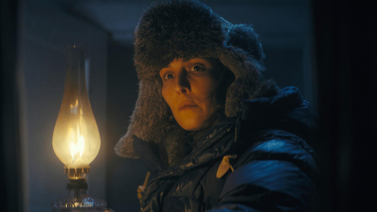  Woman holding a lit lamp. She is wearing a thick winter hat and jacket. 