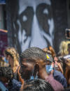 Quincy Mason Floyd, center, stands near a towering mural of his late father George Floyd, during a press conference at the spot where his father died after an encounter with police, Wednesday June 3, 2020, in Minneapolis, Minn. Floyd, a black man died after being restrained by Minneapolis police officers on May 25. (AP Photo/Bebeto Matthews)