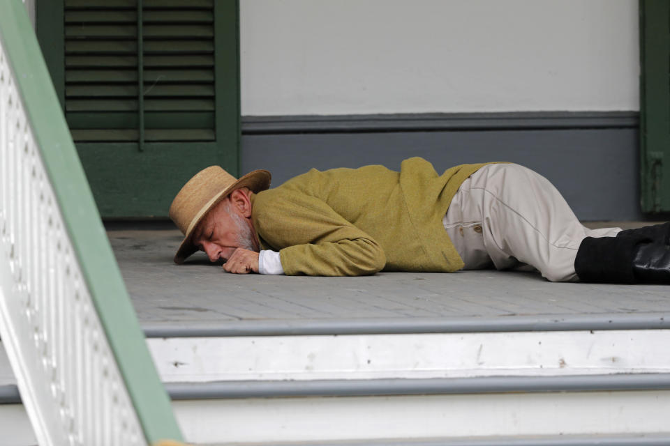 Plantation owner and slave owner Manuel Andry, portrayed by historian and photographer John, McCusker, lays wounded on the front porch of a plantation after being attacked by slaves during a performance artwork reenacting the largest slave rebellion in U.S. history in LaPlace, La., Friday, Nov. 8, 2019. The reenactment was conceived by Dread Scott, an artist who often tackles issues of racial oppression and injustice. Scott says that those who took part in the 1811 rebellion were "heroic" and that the rebellion is something that people should know about and be inspired by. (AP Photo/Gerald Herbert)