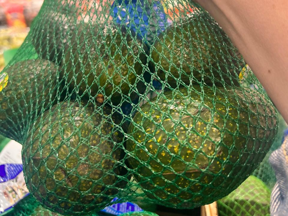 hand holding up a bulk bag of avocados at Costco