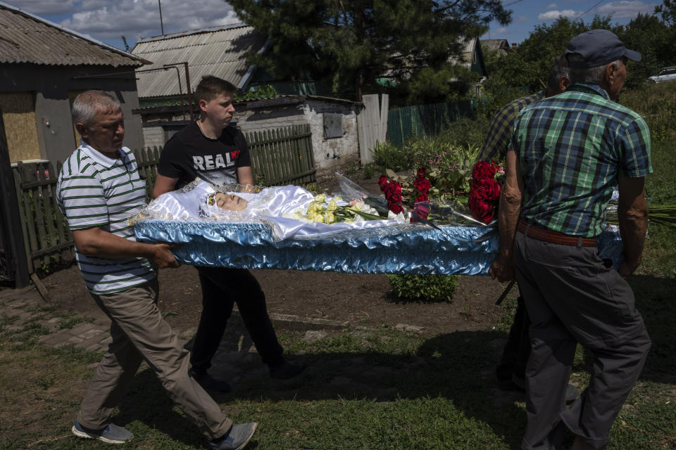 Men carry the lifeless body of 35-year-old Anna Protsenko, who was killed in a Russian rocket attack, during her funeral procession, on the outskirts of Pokrovsk, eastern Ukraine, Monday, July 18, 2022. (AP Photo/Nariman El-Mofty)