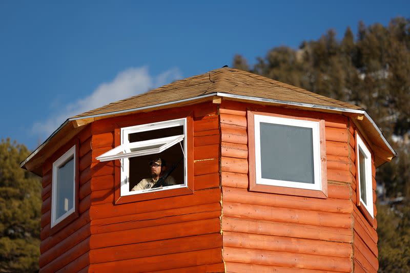 Assistant manager of a Fortitude Ranch camp stands armed in a lookout tower at a survival camp