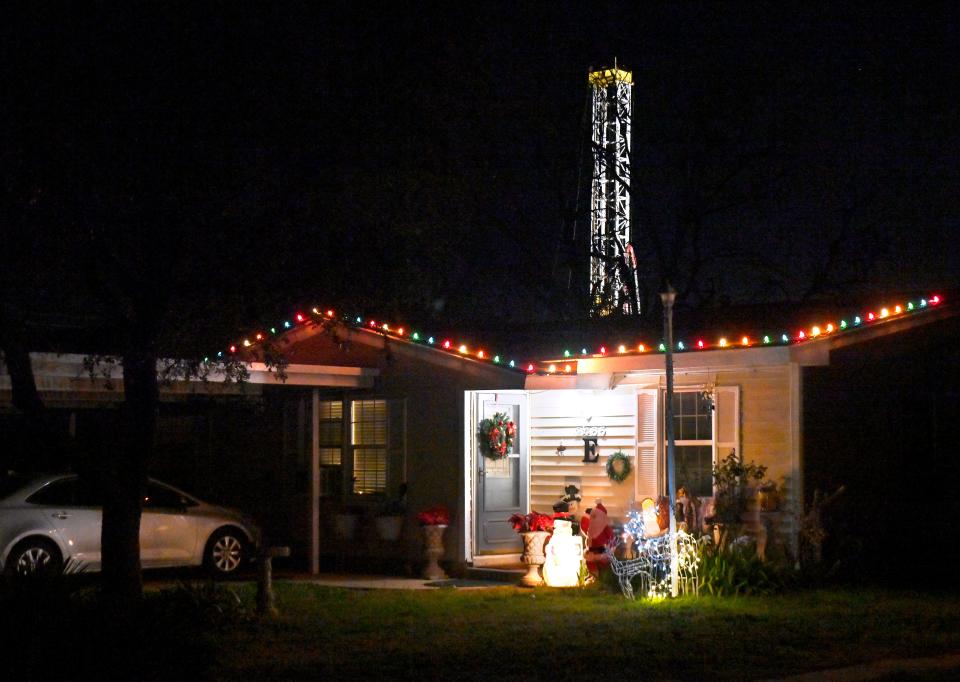 The lighted oil derrick rises behind a home on Fannin St. as drilling continued into the night one block east on Burger St. Jan. 3.
