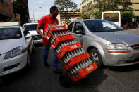 A worker pushes a dolly loaded with cases of empty Coca-Cola bottles in Caracas, Venezuela May 24, 2016. REUTERS/Carlos Garcia Rawlins