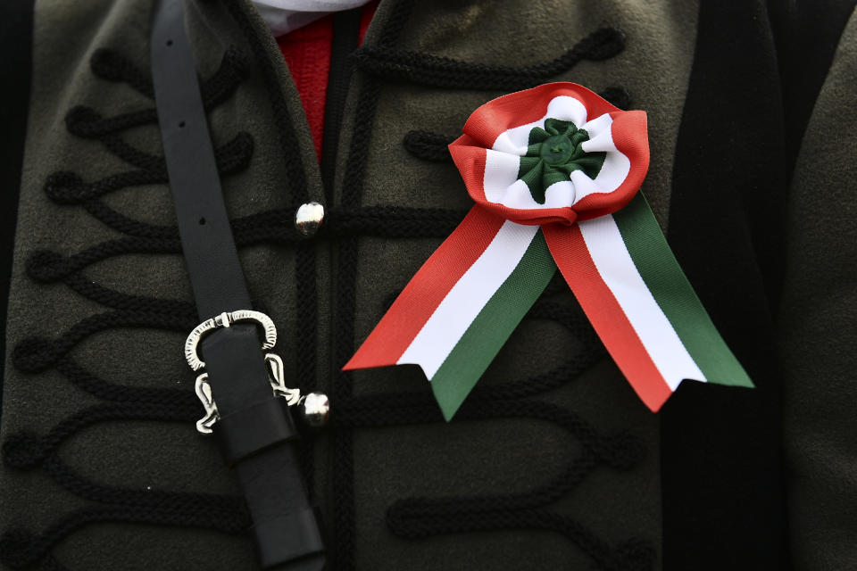 A participant wears a ribbon in Hungarian colors as thousands of supporters of Hungary's right-wing populist prime minister, Viktor Orban, gather in Budapest, Hungary, Tuesday, March 15, 2022. The so-called "peace march" was a show of strength by Orban's supporters ahead of national elections scheduled for April 3, while a coalition of six opposition parties also held a rally in the capital. (AP Photo/Anna Szilagyi)