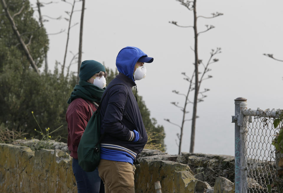 A couple standing on Alcatraz Island wear masks while looking out to the bay obscured by smoke and haze from wildfires on Thursday. (Photo: Eric Risberg/AP)