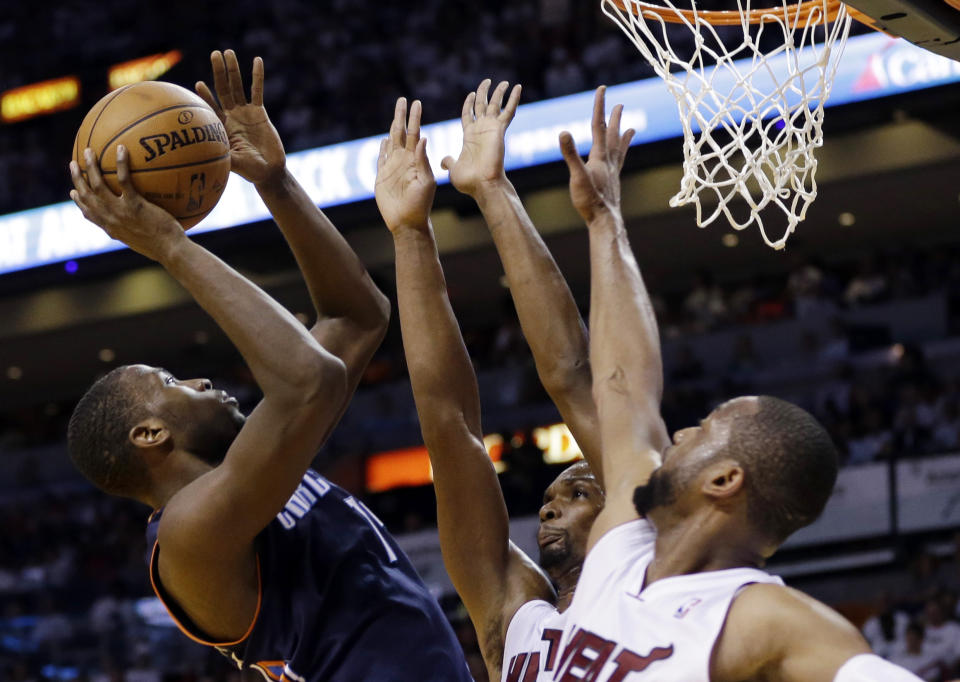 Charlotte Bobcats' Michael Kidd-Gilchrist, left, shoots as Miami Heat's Chris Bosh, center, and Dwyane Wade (3) defend during the second half in Game 2 of an opening-round NBA basketball playoff series, Wednesday, April 23, 2014, in Miami. The Heat defeated the Bobcats 101-97. (AP Photo/Lynne Sladky)