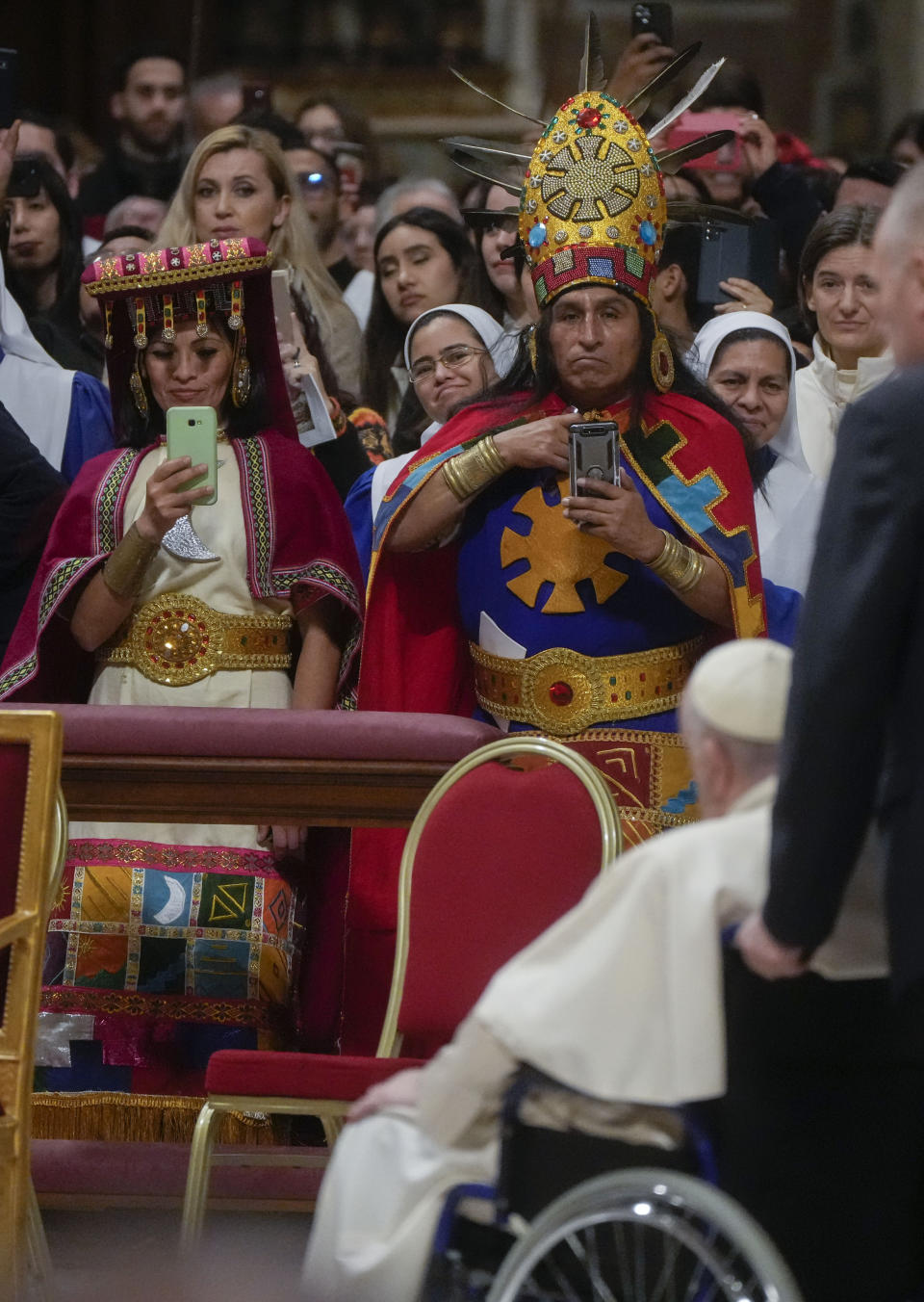 Faithful in traditional dress snaps photographs of Pope Francis at the end of a mass in honor of our lady of Guadalupe he presided over in St. Peter's Basilica at The Vatican, Monday, Dec. 12, 2022. (AP Photo/Gregorio Borgia)