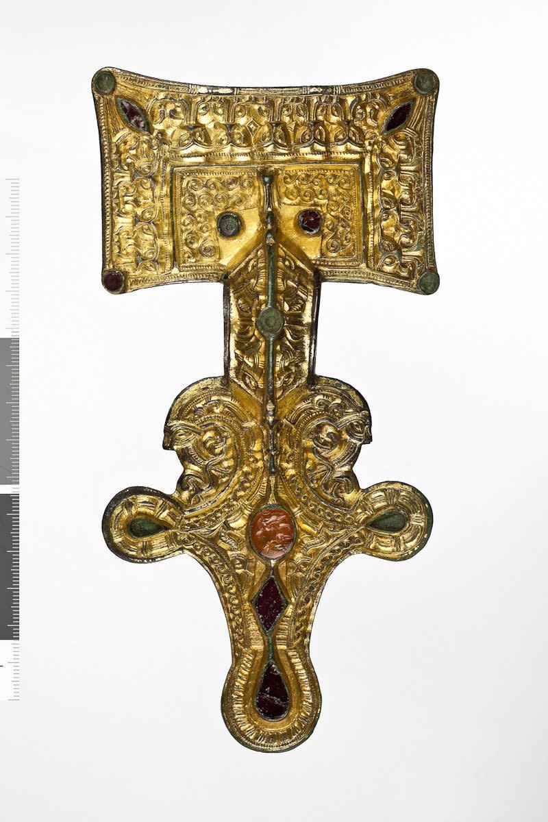 Anglo-Saxon Square-Headed Brooch with gold-gilt decoration on the front and silver plating on the back. The headplate has an outer border of zoomorphic ornamentation surrounding a panel of scroll-work. Originally the brooch was set with eleven garnets of which only six remain. In the centre is a oval carnelian from a Roman seal ring depicting Cupid milking a goat - Copyright Shakespeare Birthplace Trust/Digitisation Officer: Andrew Thomas