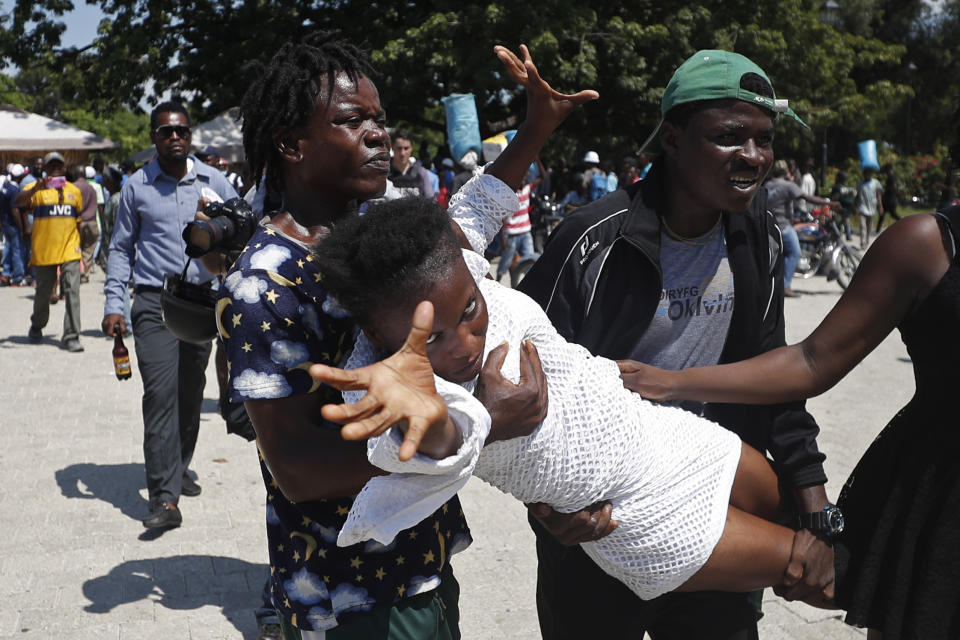 During a funeral for two people killed in violence related to recent protests, mourners hold a woman related to one of the victims after she went into a trance, at Champ de Mars park near the National Palace in Port-au-Prince, Haiti, Wednesday, Oct. 16, 2019. Funerals for 11 of at least 20 people killed were held in six cities, including the capital of Port-au-Prince, where at least two people were injured in a protest that broke out when presidential guards tried to block a road near where hundreds had gathered around the coffins of two victims. (AP Photo/Rebecca Blackwell)