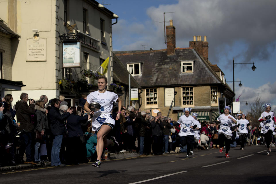 First place finisher Devon Byrne, left, from Olney, leads the field en route to winning the annual Shrove Tuesday trans-Atlantic pancake race for the third time in a record time of 55.61 seconds, in the town of Olney, in Buckinghamshire, England, Tuesday, March 4, 2014. Every year women clad in aprons and head scarves from Olney and the city of Liberal, in Kansas, USA, run their respective legs of the race with a pancake in their pan, flipping it at the beginning and end of the race. According to legend, the Olney race started in 1445 when a harried housewife arrived at church on Shrove Tuesday still clutching her frying pan with a pancake in it. Liberal challenged Olney to a friendly international competition in 1950 after seeing photos of the race in a magazine. (AP Photo/Matt Dunham)