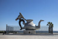 A man sits next to a tea jug monument in central Dakhla, Western Sahara, Monday, Dec. 21, 2020. U.S. plans to open a consulate in Western Sahara mark a turning point for the disputed and closely policed territory. U.S. recognition of Morocco’s authority over the land frustrates indigenous Sahrawis seeking independence. But others see the future U.S. consulate as a major boost for Western Sahara cities like Dakhla. (AP Photo/Mosa'ab Elshamy)