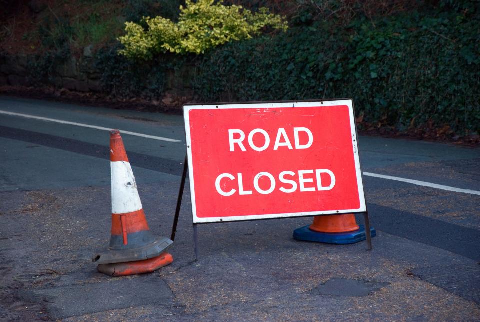 Sign and cones indicating that the road ahead is closed.