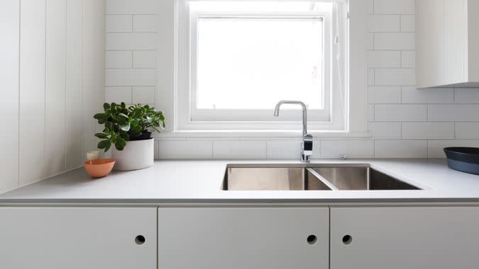 Close up details of contemporary white apartment kitchen with subway tiles.
