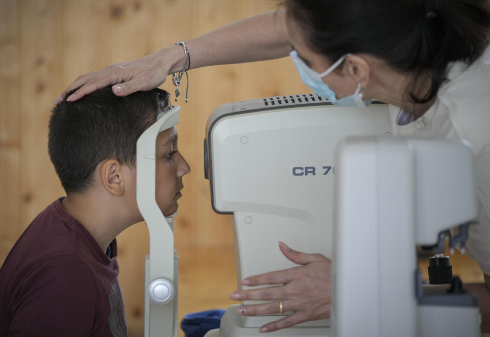 A boy undergoes an eyesight examination performed by volunteer ophthalmologists, in Nucsoara, Romania, Saturday, May 29, 2021. Dozens of disadvantaged young Romanian children got a chance to get their eyesight examined for the first time in their lives during an event arranged by humanitarian organization Casa Buna, or Good House, which has played a prominent role in supporting the local children's lives throughout the pandemic. (AP Photo/Vadim Ghirda)