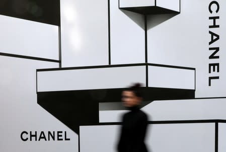 FILE PHOTO: A woman walks past the logos of French luxury goods maker Chanel in Nice