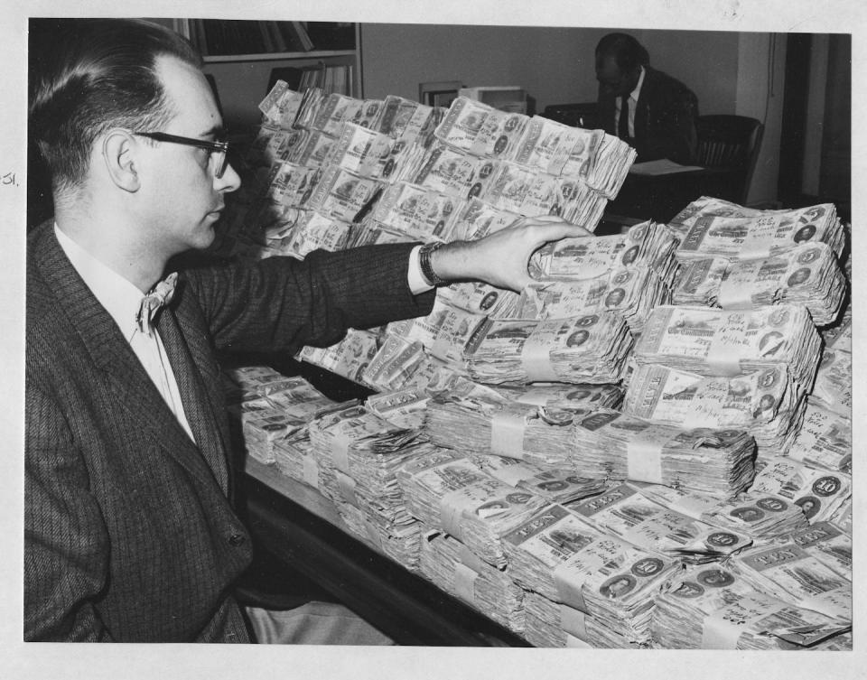 A man in glasses looks at stacks of Confederate currency