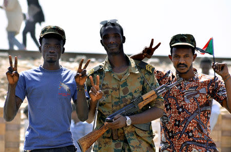 A Sudanese military officer and demonstrators gesture in celebration after Defence Minister Awad Ibn Auf stepped down as head of the country's transitional ruling military council, as protesters demanded quicker political change, near the Defence Ministry in Khartoum, Sudan April 13, 2019. REUTERS/Stringer