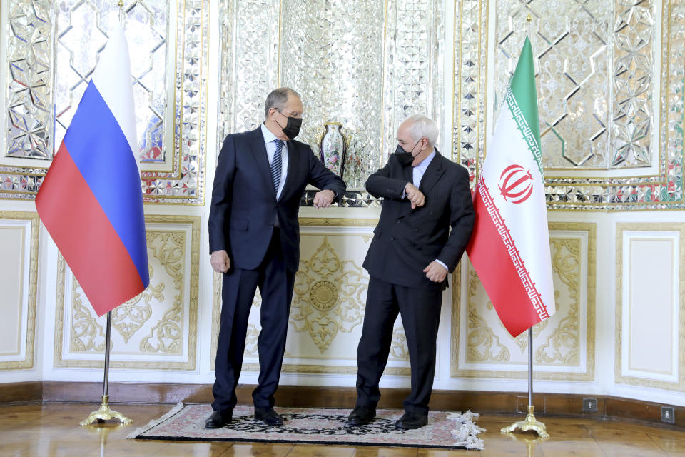 In this photo released by the Iranian Foreign Ministry, Iranian Foreign Minister Mohammad Javad Zarif, right, and Russian Foreign Minister Sergey Lavrov greet each other by touching elbows and wear face masks to curb the spread of COVID-19 prior to their talks in Tehran, Iran, Tuesday, April 13, 2021. Iran's foreign minister warned Tuesday that an attack on its main nuclear enrichment site at Natanz affects ongoing negotiations in Vienna over its tattered atomic deal with world powers. (Iranian Foreign Ministry via AP)