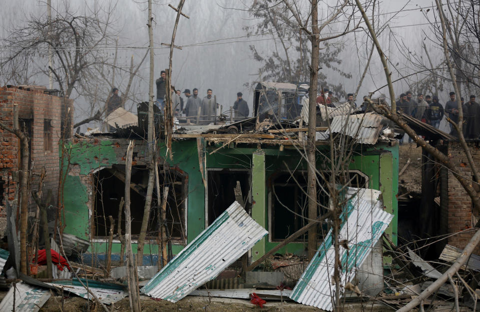 Kashmiri villagers watch the damage caused to residential houses at the site of a gun-battle in Mujagund area some 25 Kilometers (16 miles) from Srinagar, Indian controlled Kashmir, Sunday, Dec. 9, 2018. Indian troops killed three suspected rebels in the outskirts of disputed Kashmir's main city ending nearly 18-hour-long gunbattle, officials said Sunday. (AP Photo/Mukhtar Khan)