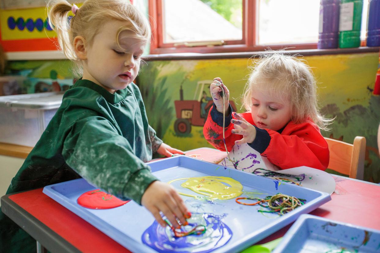 Two girls painting at a nursery school in the UK