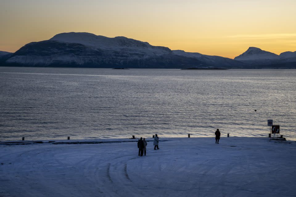 Several people are walking along the shores of the Norwegian Sea.