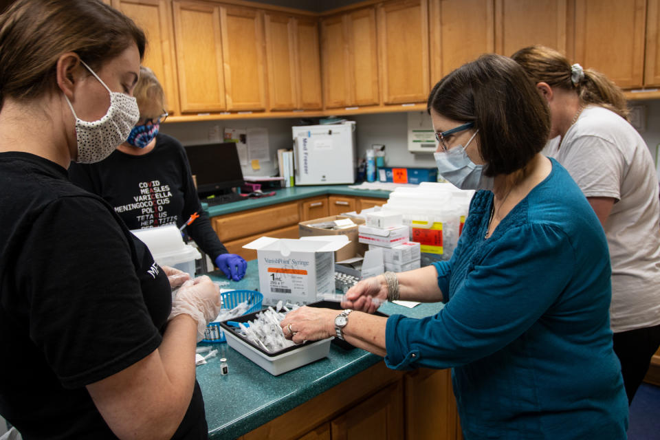 Dr. Jane Wilkov, in blue at right, prepares needles and doses of the Pfizer coronavirus vaccine on Wednesday, May 12, 2021, in Decatur, Ga. Hundreds of children, ages 12 to 15, received the Pfizer vaccine at the DeKalb Pediatric Center, just days after it was approved for use within their age group. (AP Photo/Ron Harris)