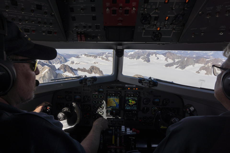 In this photo taken on Wednesday, Aug. 14, 2019, pilots Andy Ferguson, left, and Don Watrous, fly a plane carrying NASA scientists on a mission to track melting ice in eastern Greenland. Greenland has been melting faster in the last decade and this summer, it has seen two of the biggest melts on record since 2012. (AP Photo/Mstyslav Chernov)