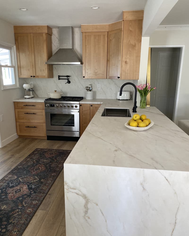 white kitchen with wood cabinets and marble counter and backsplash after makeover