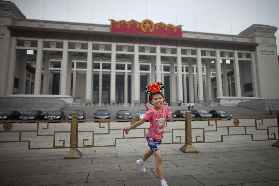 In this Monday, July 9, 2012 photo, a girl wearing Qing Dynasty royal style headset plays outside China's National Museum on the east of the Tiananmen Square in Beijing. Tiananmen Square, the world's largest public square, is surrounded by buildings of political and cultural significance and is visited by thousands of tourists daily. (AP Photo/Alexander F. Yuan)