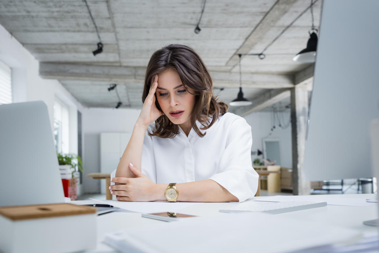 Female entrepreneur with headache sitting at desk. Businesswoman under terrible physical tension at work.