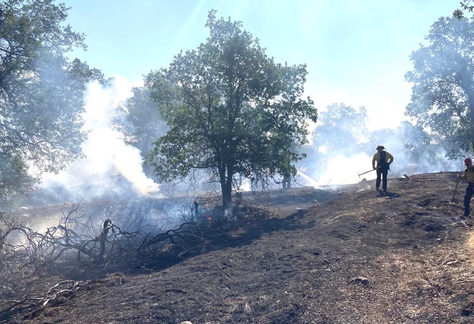 Crews mop up a small vegetation fire that burned in the area of Stone Canyon Drive and Quartz Hill Road on Friday, June 23, 2023.