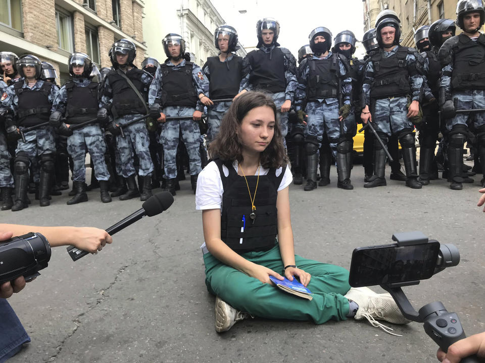 In this Saturday, July 27, 2019, photo, provided by Alexei Abanin, Olga Misik, member of the small, grassroots group Bessrochka, sits in front of police officers during an unsanctioned rally in the center of Moscow. Despite the group’s small numbers, its use of new digital tools and efforts to self-organize mark a shift in civil consciousness previously unseen in Russia. (Alexei Abanin via AP)