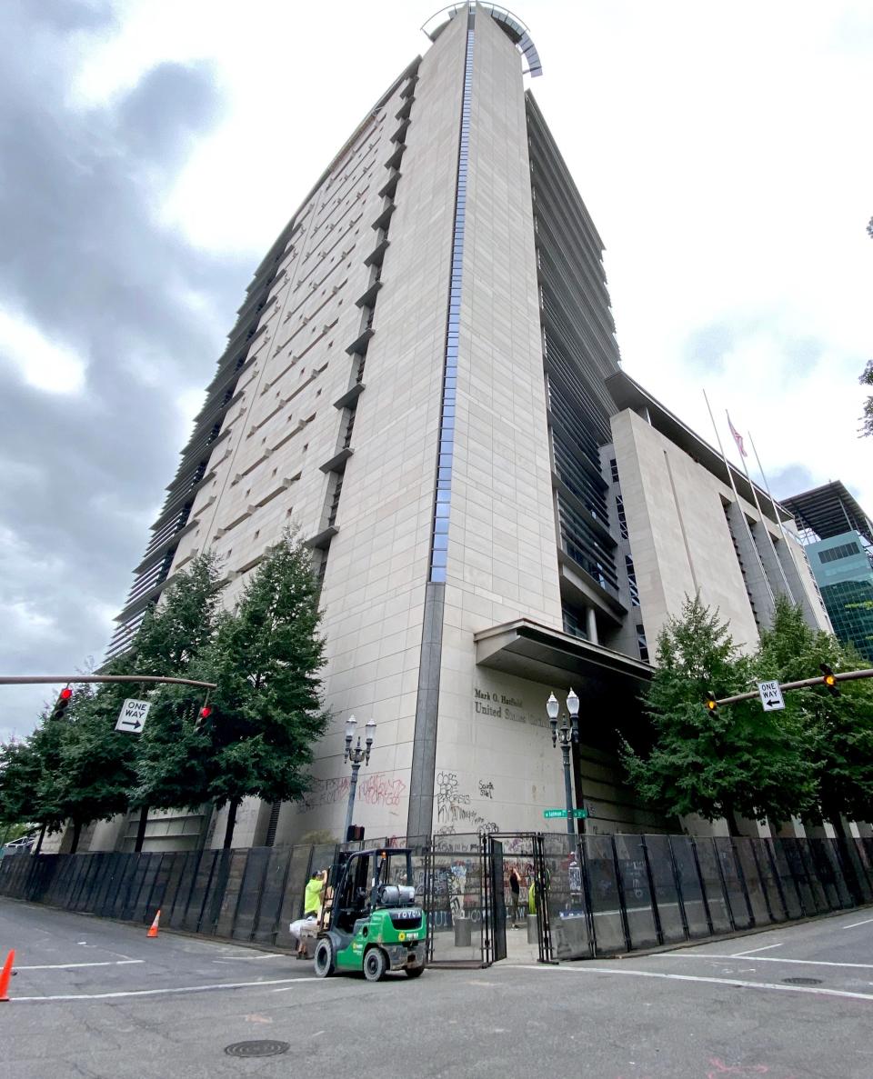 Workers erect metal fencing and concrete barriers around the federal courthouse in Portland, Ore., on July 22.