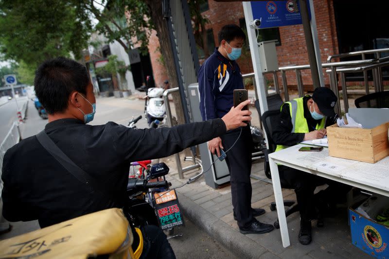 Delivery driver holds up his smartphone to present the status of his health app in Beijing